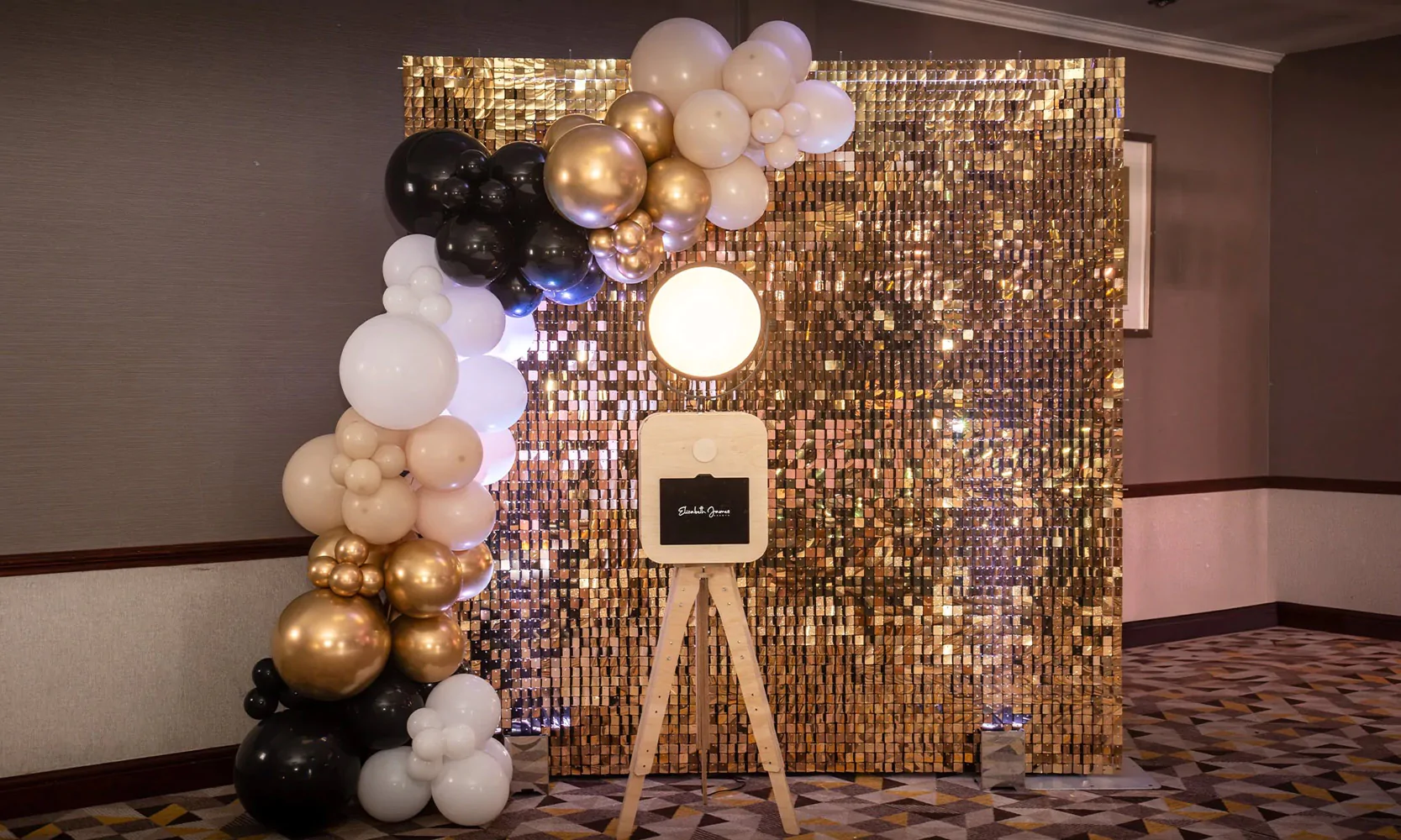 Photo booth with gold sequin wall and balloons.