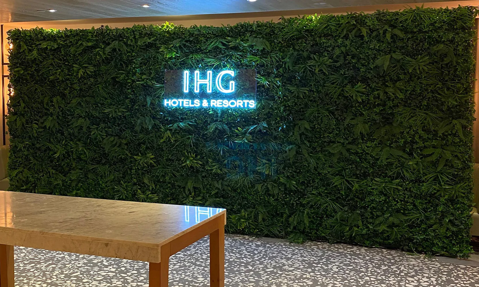 Faux foliage wall with custom branded neon sign by Elizabeth James Events.