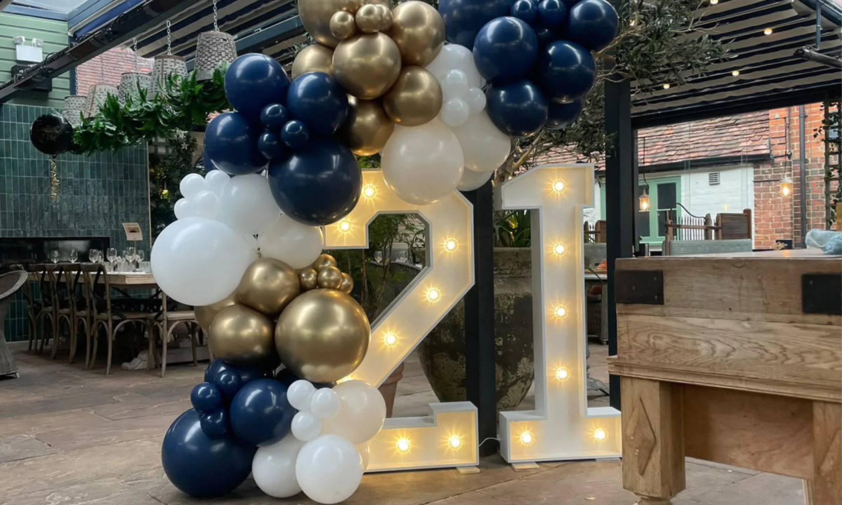 Birthday party decor featuring '21' in light-up letters with a bespoke balloon garland.