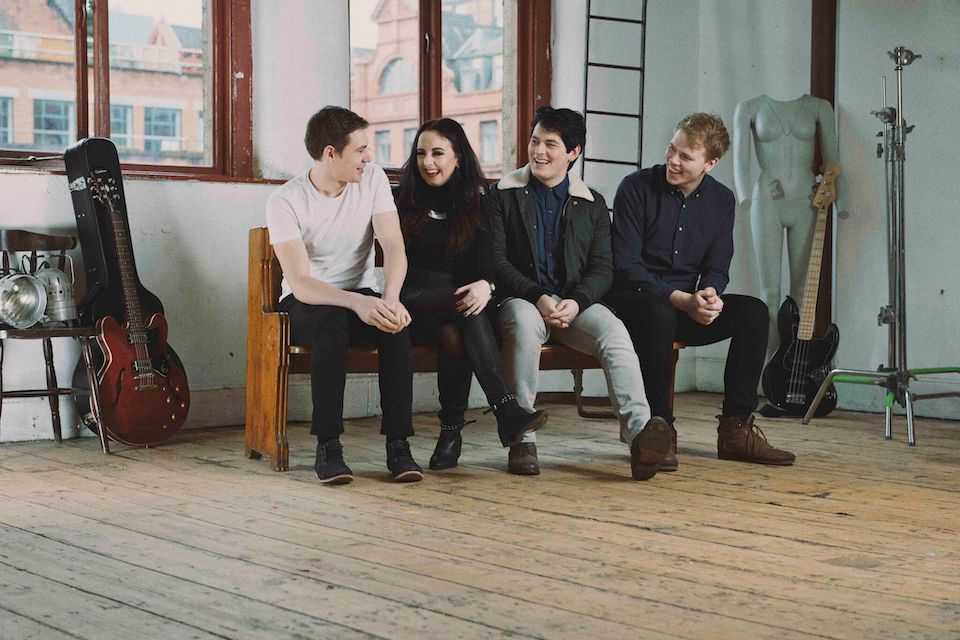 Members of a band sitting on a bench laughing together